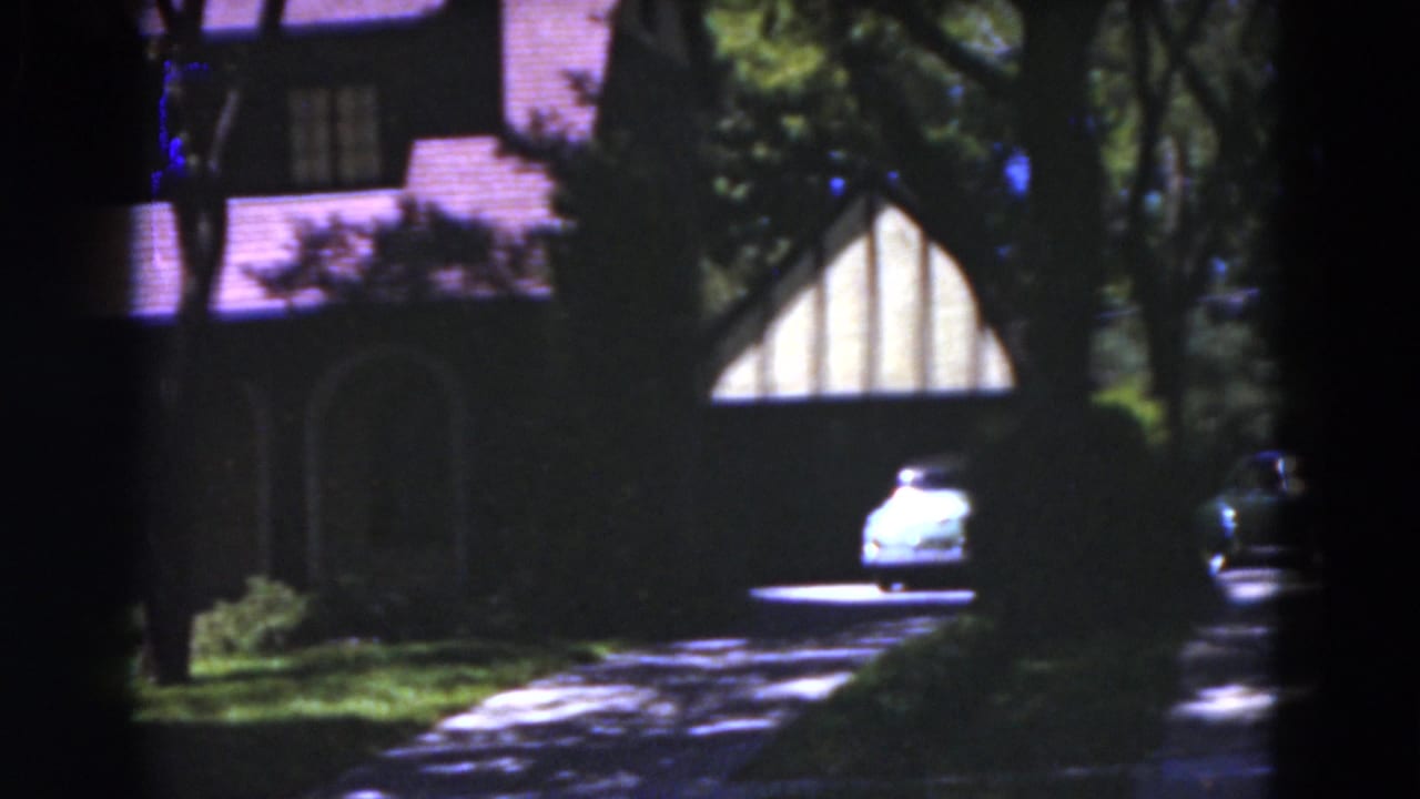 House exterior with driveway, trees and a light car near the garage.
