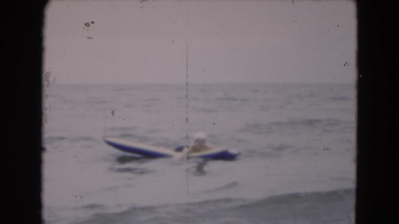 Woman floating on a blue-and-white raft in open ocean water.