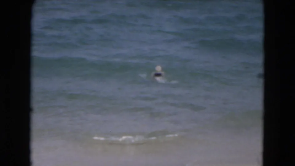 1975 Florida beach footage shows a person bobbing nearer the shore in shallow, softly focused ocean water.