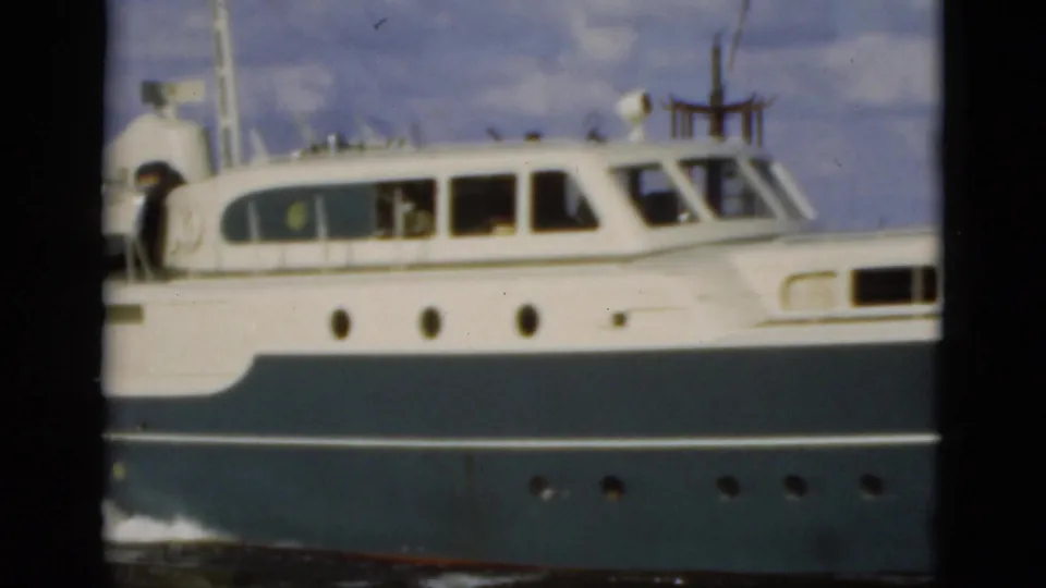 1975 Florida 8mm frame showing a white and blue motor yacht in side profile, with cabin windows and portholes visible above the waterline.