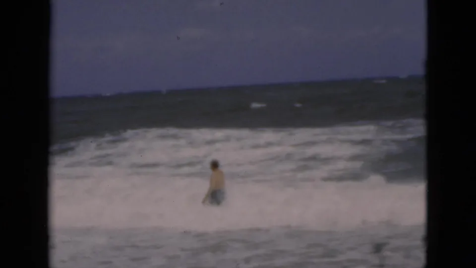 The man remains in the Florida surf, partly surrounded by foam as rolling waves fill the background in the 8mm frame.