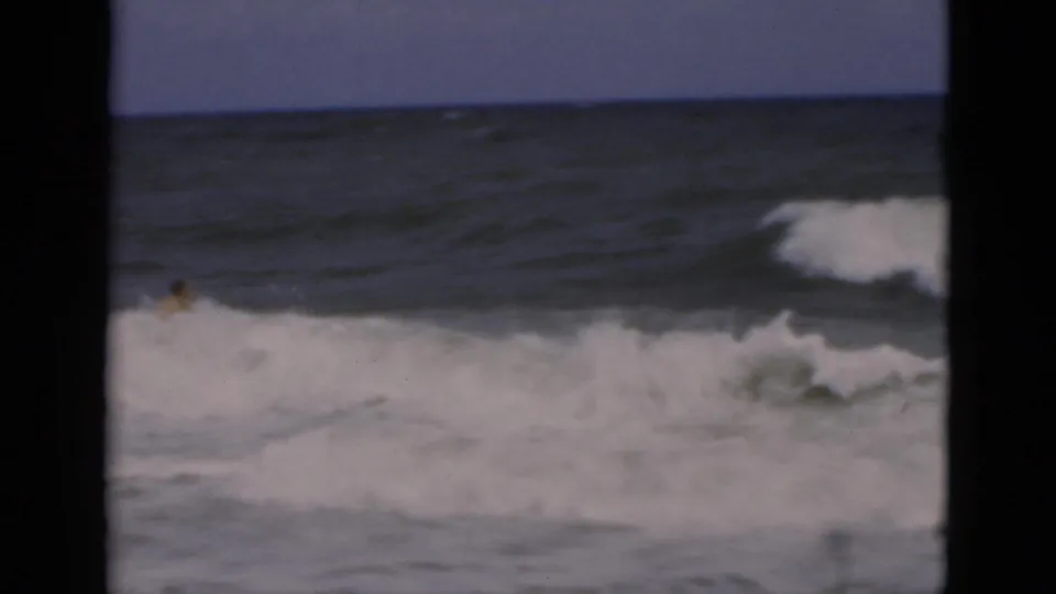 The swimmer is largely hidden by breaking white water as rough surf fills the 1975 Florida beach frame.