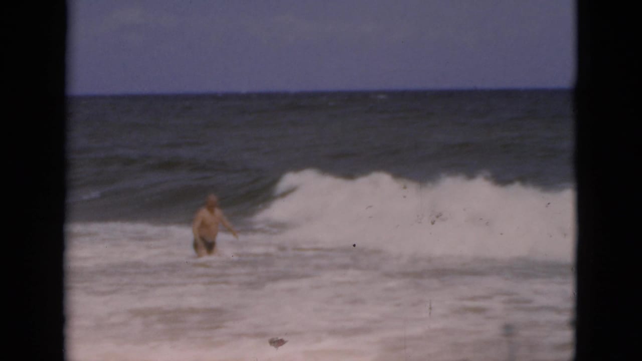 1975 Florida beach footage shows an adult man in the water with white-capped waves breaking nearby.