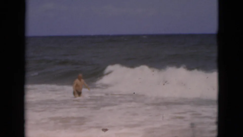 1975 Florida beach footage shows an adult man in the water with white-capped waves breaking nearby.