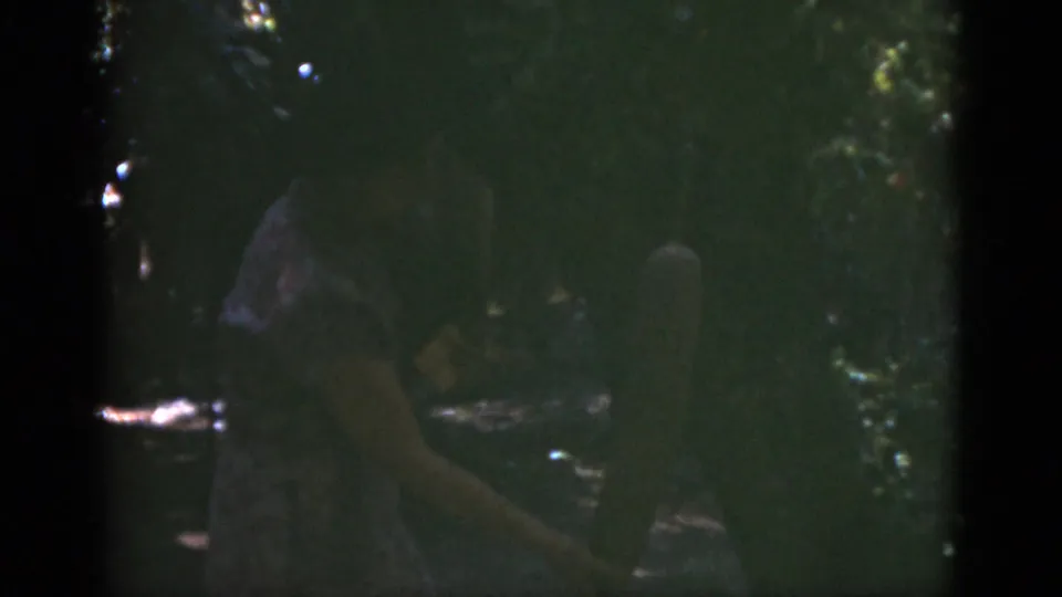 A woman in a garden appears partly obscured by shadow and foliage in this 1975 Florida 8mm home-movie frame.