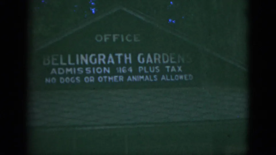 1975 8mm frame showing a green Bellingrath Gardens office sign with admission price and visitor rule text.