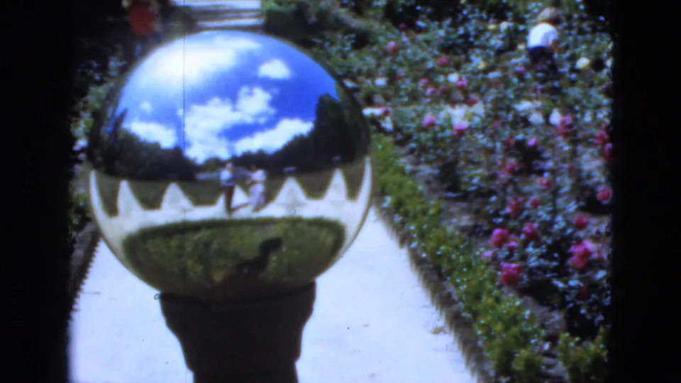 1951 Florida garden frame with a mirrored sphere reflecting sky, path, flower beds, and small visitor figures.