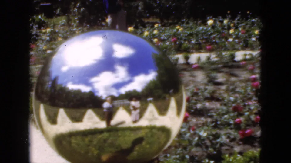 The reflective sphere remains centered in the Florida garden, mirroring clouds, lawns, walkway geometry, and visitors in the grounds.