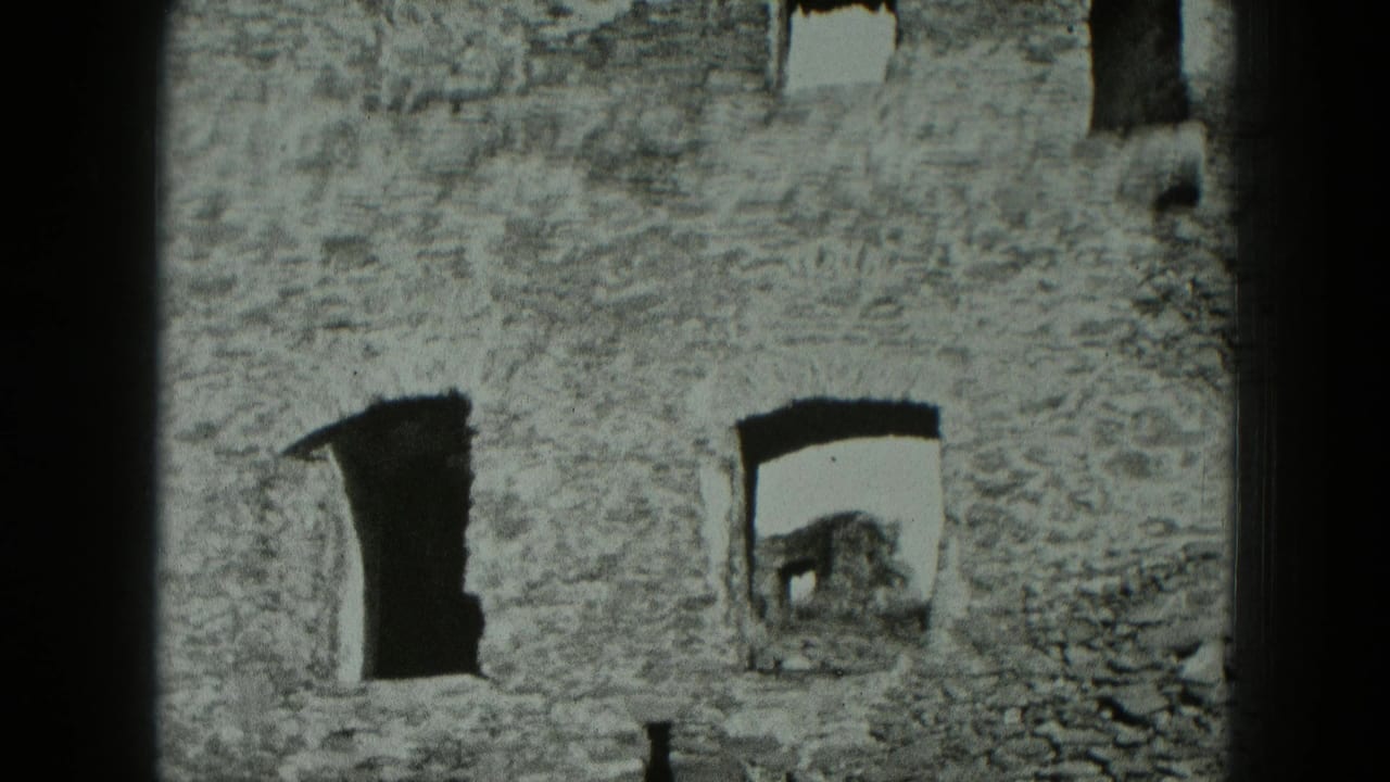 1951 West Germany 8mm frame of a weathered stone building facade with empty window openings and uneven masonry.