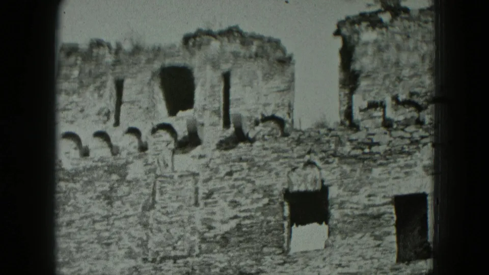 Black-and-white 8mm view of German castle fortress ruins, with rough stonework, arched gaps, and dark rectangular openings.