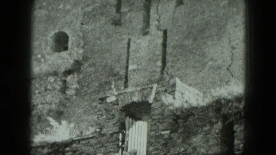 1951 Germany 8mm frame showing a damaged brick building wall with arched window openings and rough masonry edges.