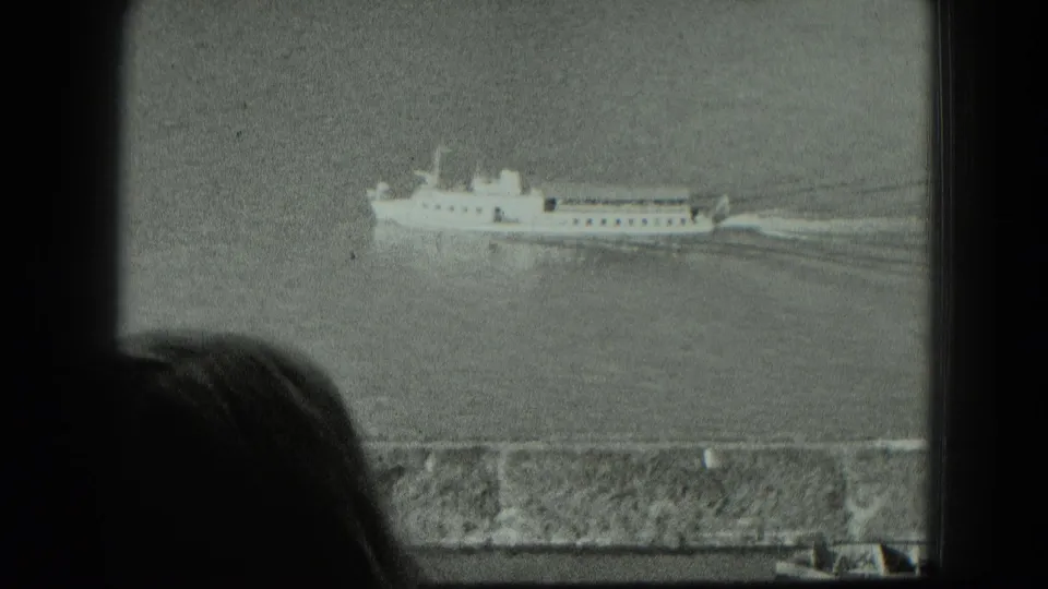 1951 West Germany home-movie frame showing a passenger vessel on calm water, viewed from behind a dark foreground silhouette and wall.