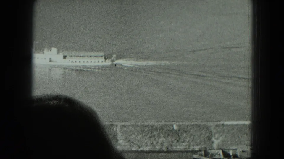 1951 West Germany 8mm frame with the passenger vessel partly at left, wake behind it, and a silhouetted viewer near the lower edge.