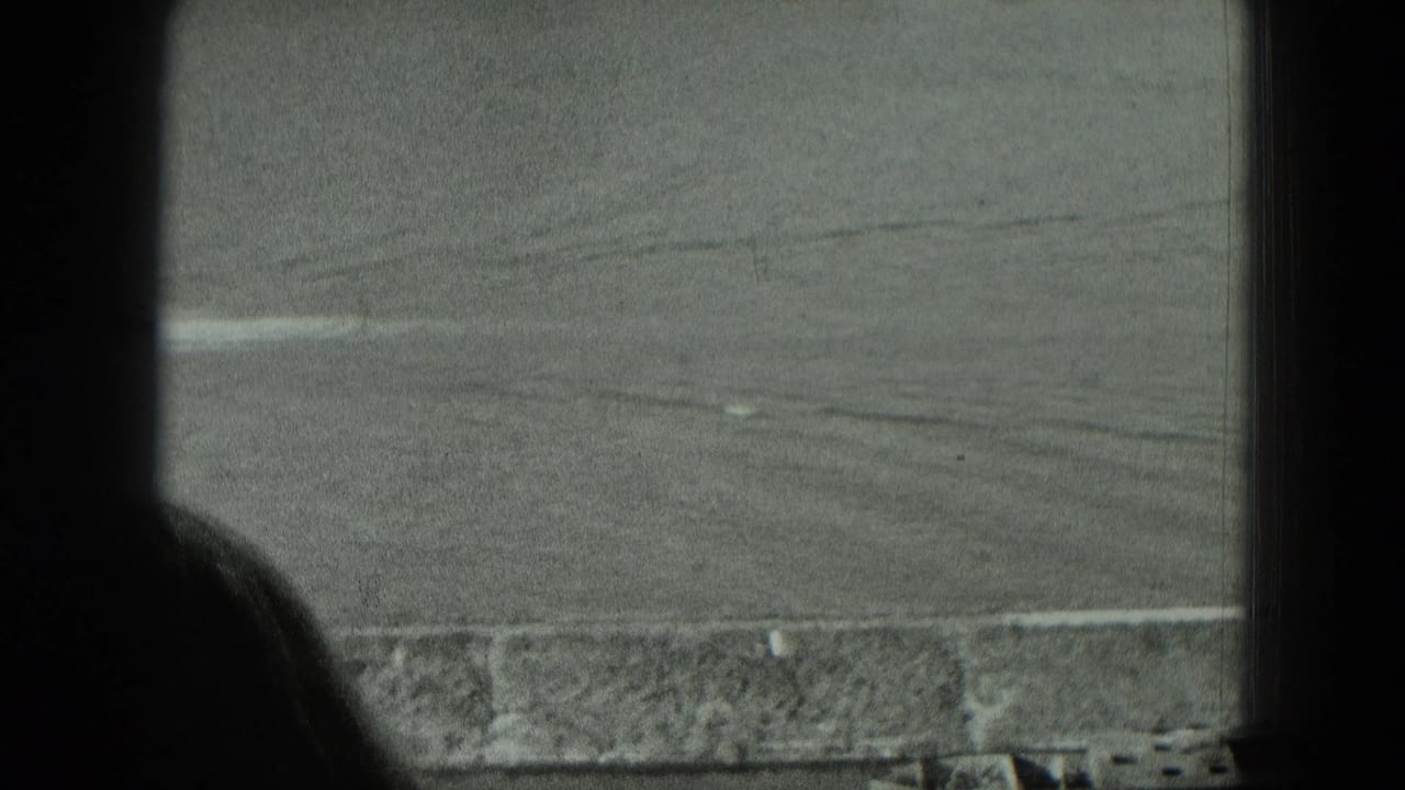 Window mullion and head silhouette frame a distant riverbank with open land beyond.