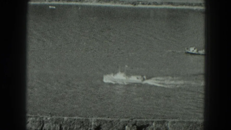 1951 German river footage frame with a small boat crossing the water and a strong white wake trailing behind.