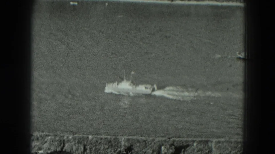 Black-and-white 8mm frame from Germany in 1951 showing a small boat on open river water near a low shoreline edge.