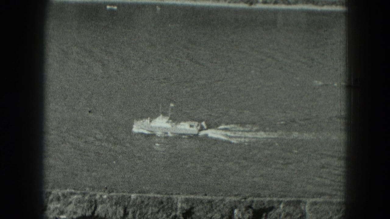 Small boat moving across calm water with a low shoreline and film-frame borders visible.