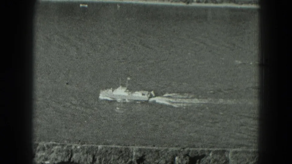 1951 Germany 8mm frame showing a small vessel crossing calm water near a low embankment, with soft grain and gate edges.