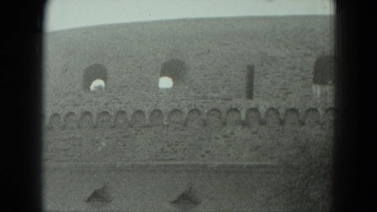 1951 West Germany home-movie frame showing a weathered stone fortress wall with arched windows and a crenellated edge.