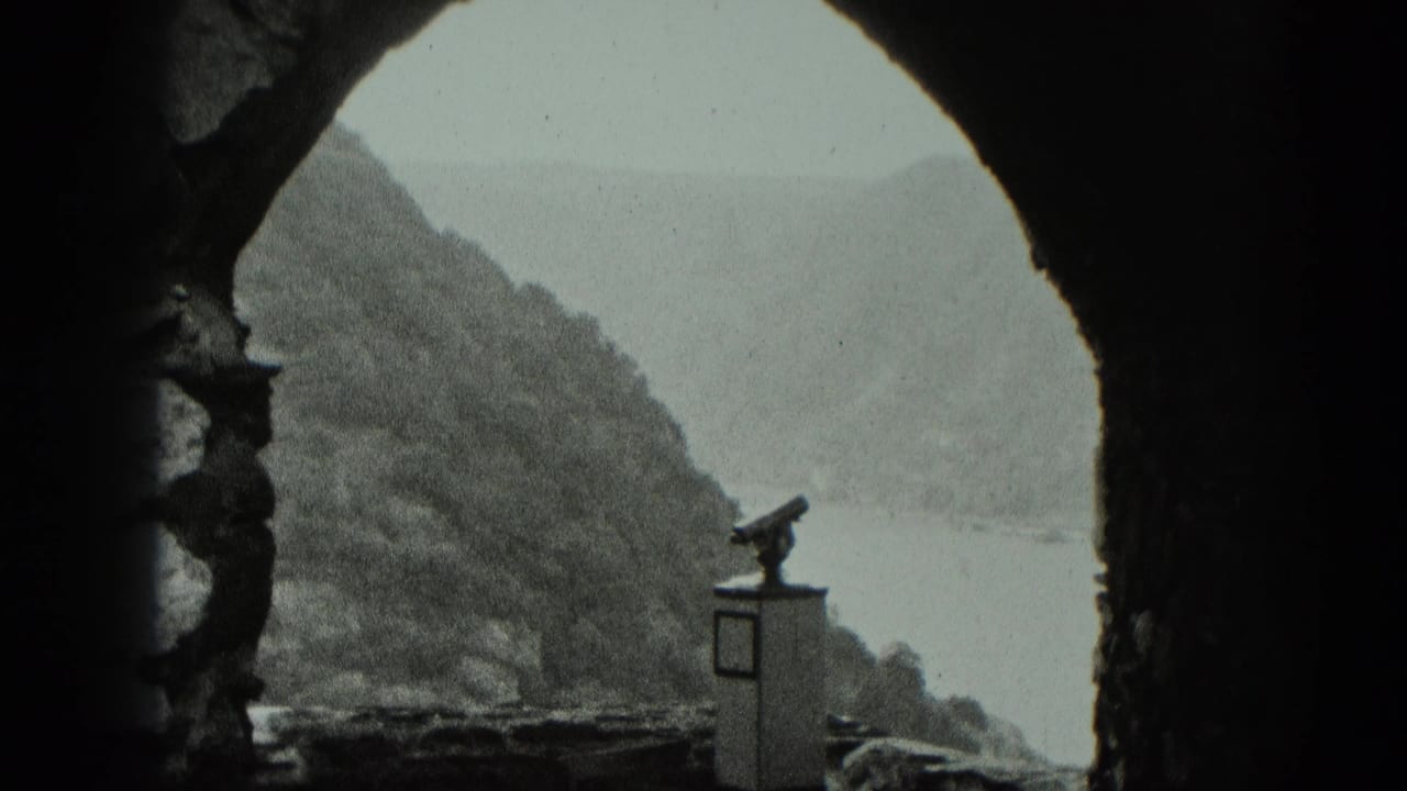 Stone archway frames a river valley in West Germany, with a coin-operated binocular viewer near the overlook.