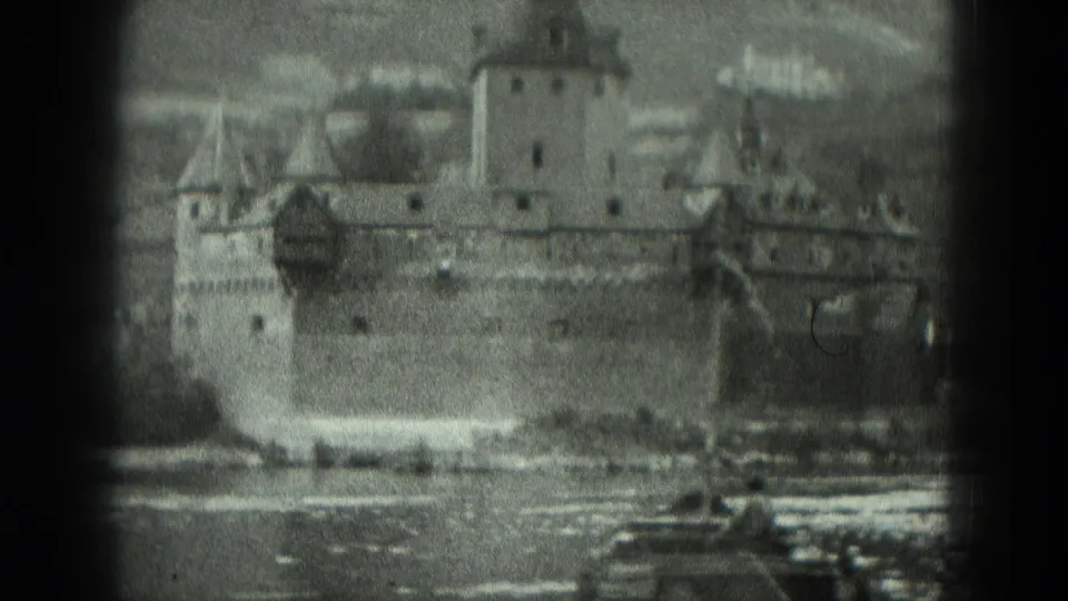 1951 Germany home-movie frame with a closer view of the stone fortress, central tower, river water, and a small boat near the foreground.