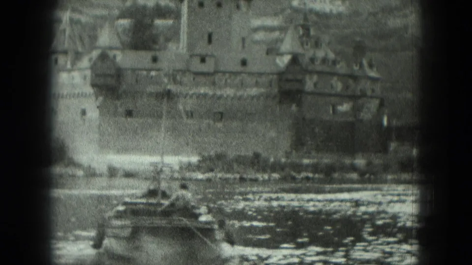1951 Germany frame showing the fortress above the river as a small boat passes in the foreground and hillside rises behind the walls.