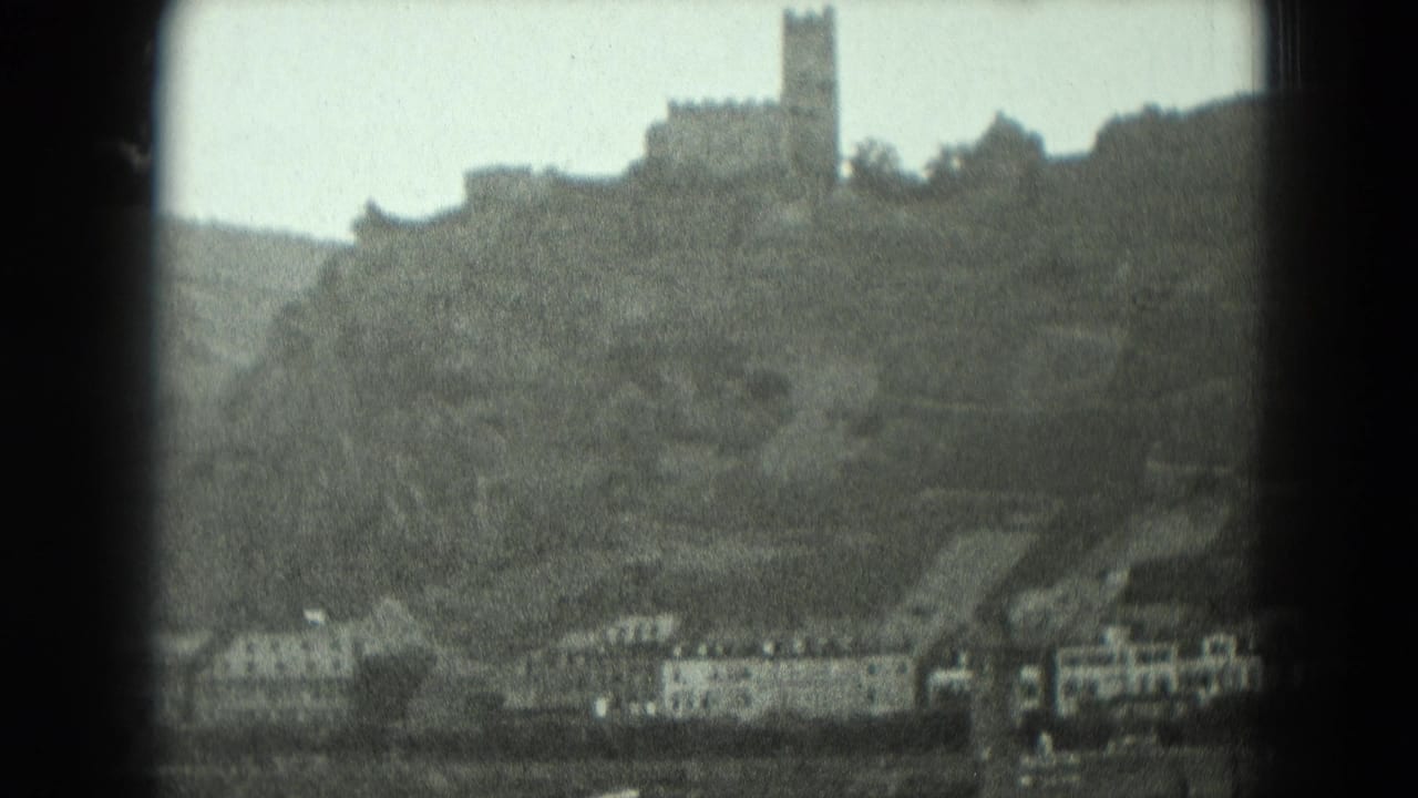 Soft black-and-white view of a German hillside castle and tower above riverside structures in 1951 home-movie footage.