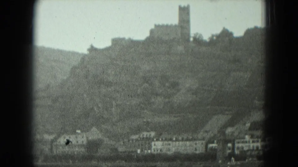 Visitor-shot 8mm view of a German riverbank, hillside, and castle tower seen from a boat in 1951.