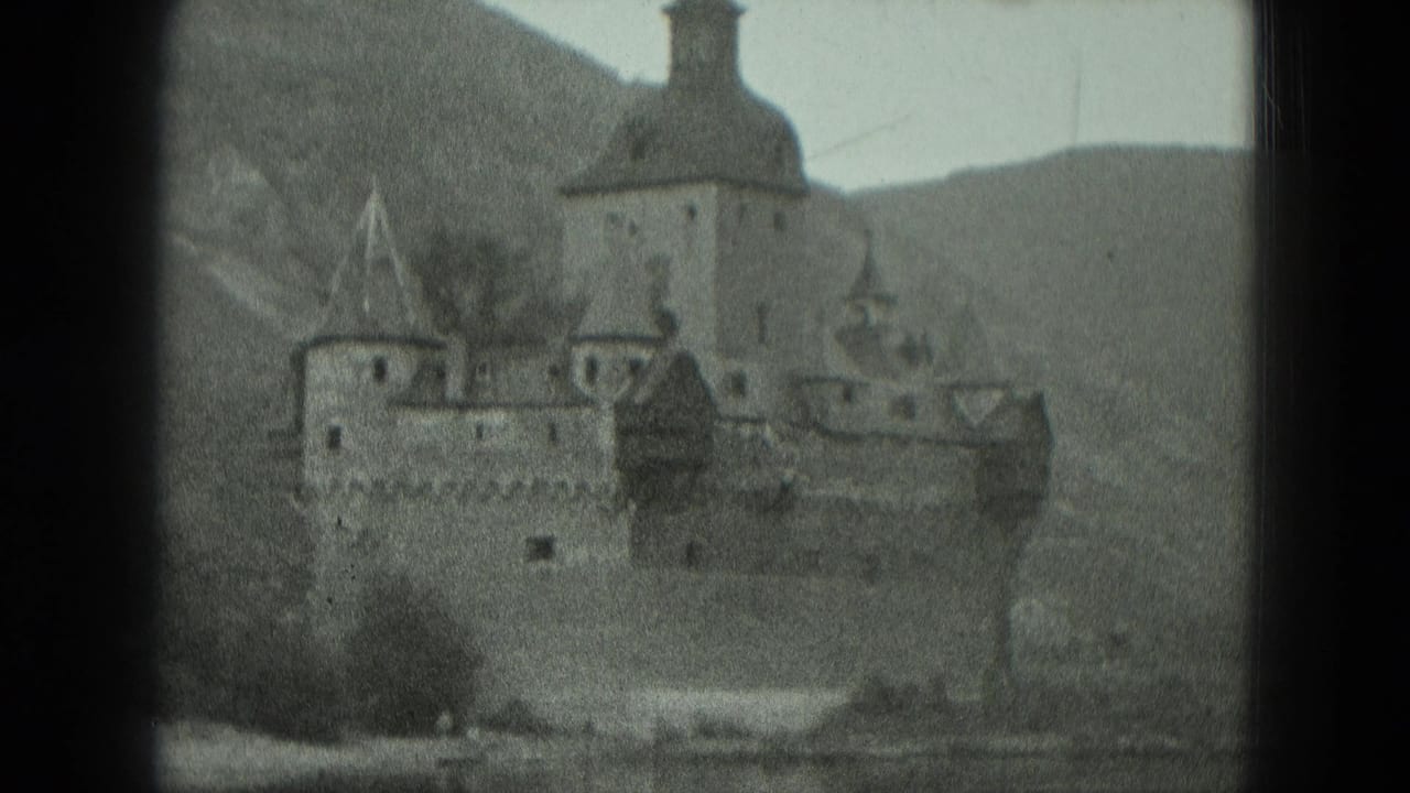 Black-and-white 1951 8mm view of a castle-like riverside structure in Germany, framed by dark gate edges and hills.