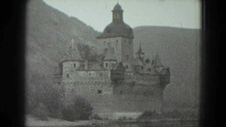 1951 West Germany home-movie view of a hillside castle with a domed tower, stone walls, and surrounding wooded slope.