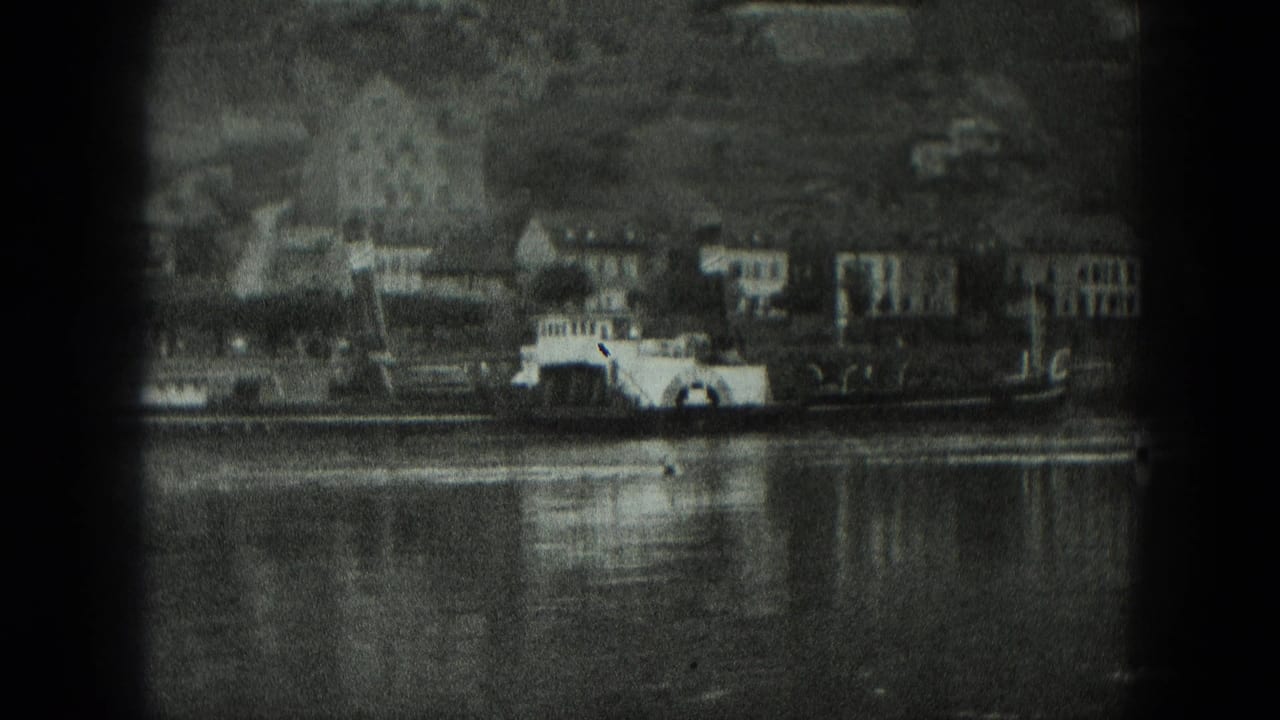 Riverside town with waterfront buildings and a paddlewheel-style boat on the water.