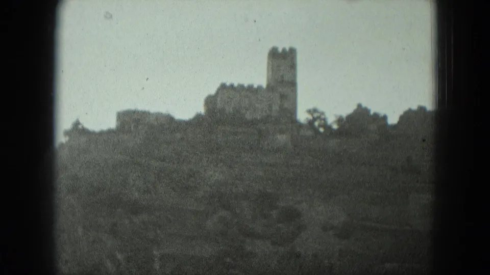 1951 West Germany home-movie shot of a distant hilltop castle or ruin with a square tower silhouetted against a pale sky.
