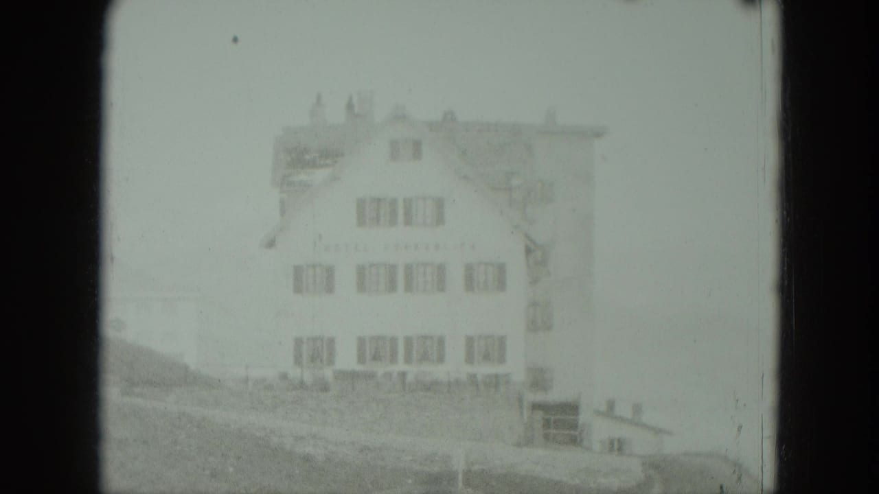 Large pale house on a misty hillside, framed by dark 8mm film edges.