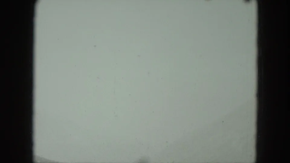 Soft, nearly featureless 8mm frame with pale exposure, gate edges, and minor dust from the Germany home-movie clip.