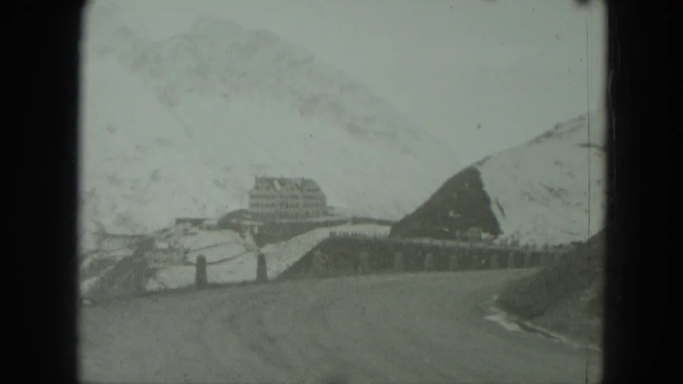 1951 8mm footage of a snow-covered German mountain road approaching a large distant building in overcast conditions.