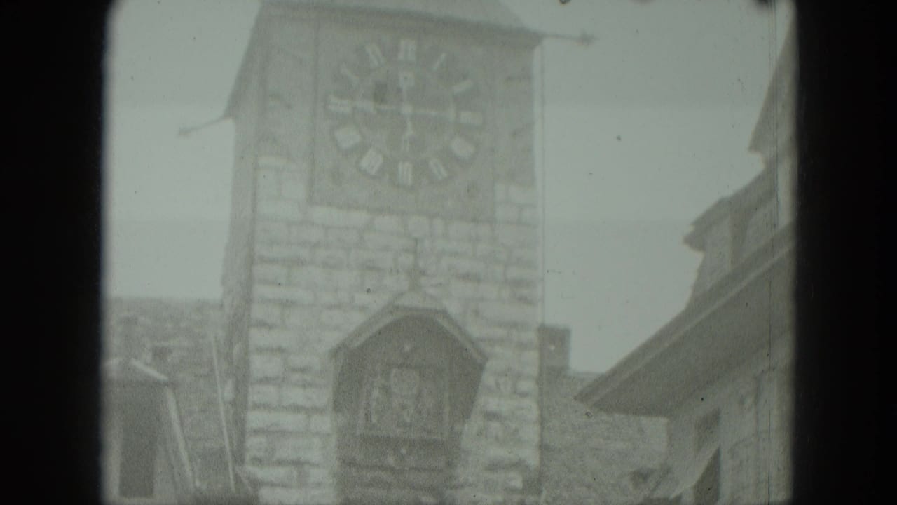 Clock tower and cuckoo-clock structure framed beside neighboring rooflines.
