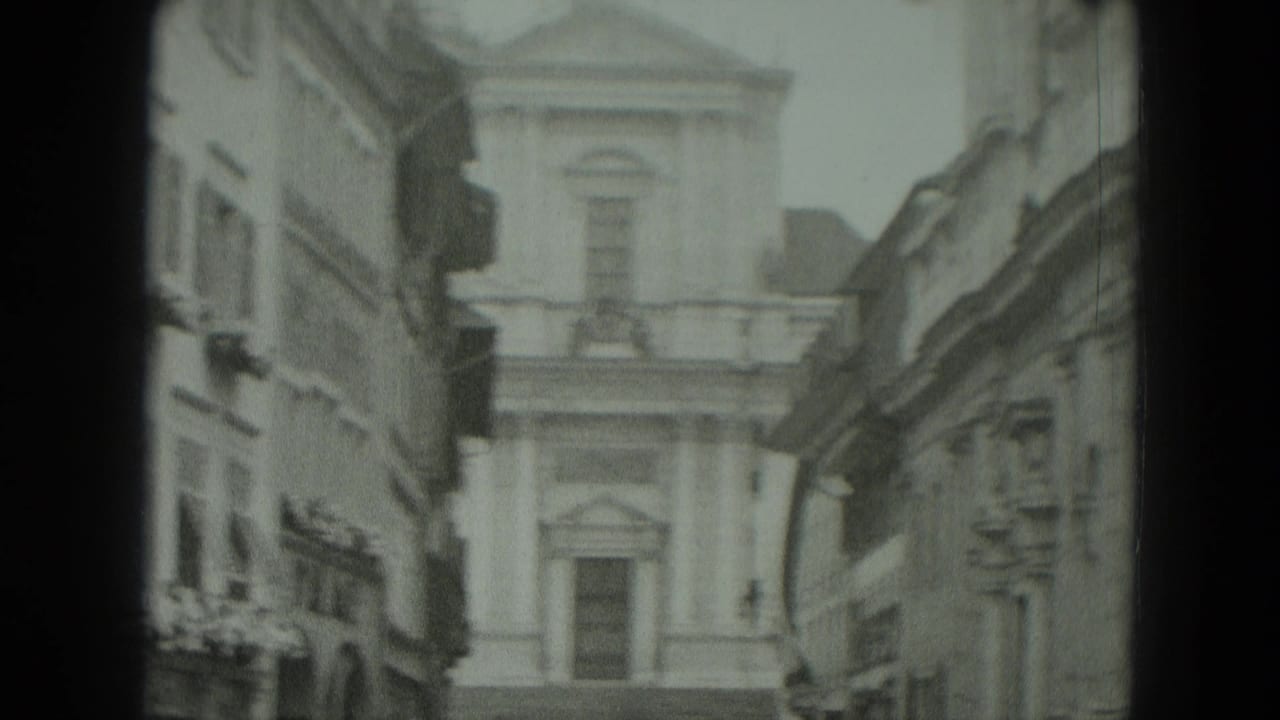 Soft black-and-white view of a classical building at the end of a narrow town street.