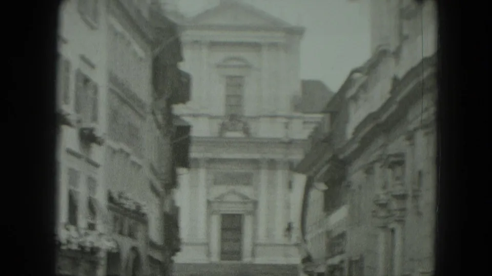 1951 West Germany home-movie frame showing a classical facade framed by older town buildings and dark 8mm film borders.