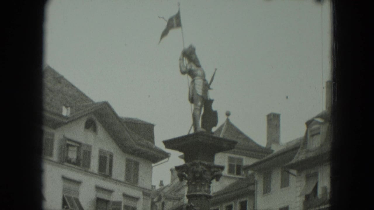 Column statue framed against rooftops and surrounding market-square buildings.