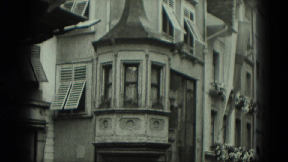 1951 West Germany frame showing a close architectural view with a bay window, open shutters, flower boxes, and narrow facades.