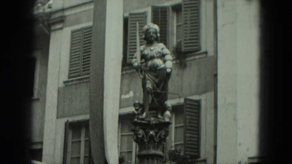 Closer 1951 Germany home-movie view of the stone figure, pedestal details and surrounding shuttered windows.