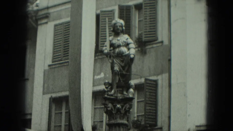 1951 Germany frame centering the stone statue and pedestal between shuttered windows and pale building walls.
