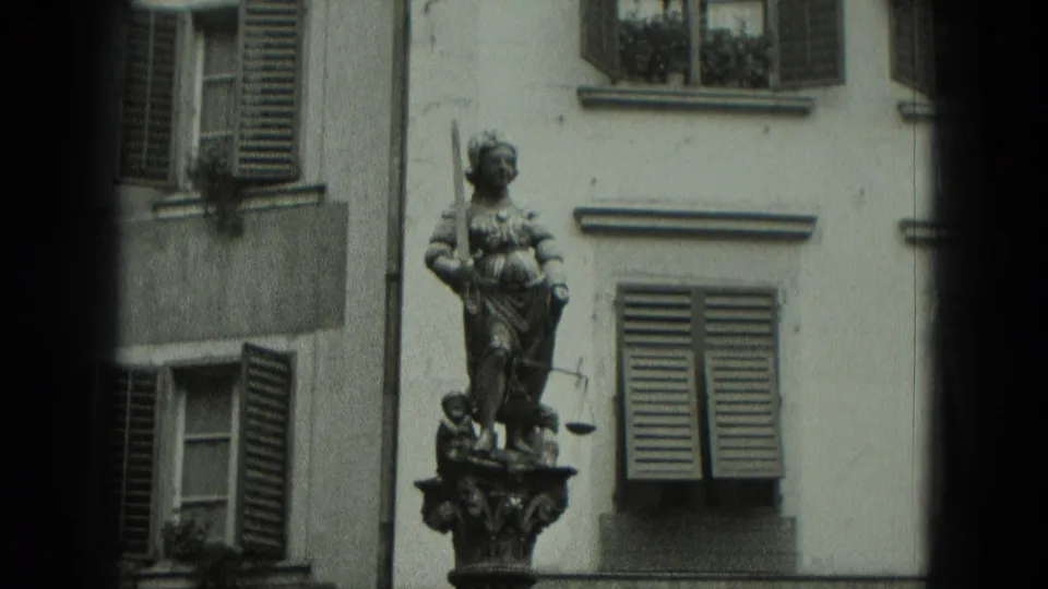 1951 West Germany frame of a public statue and nearby louvered shutters on a pale old-building facade.