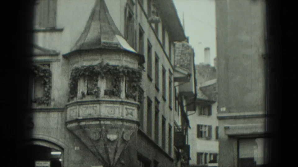 1951 West Germany frame of a narrow old street with a decorative bay window, ivy, shuttered windows, and tall facades.