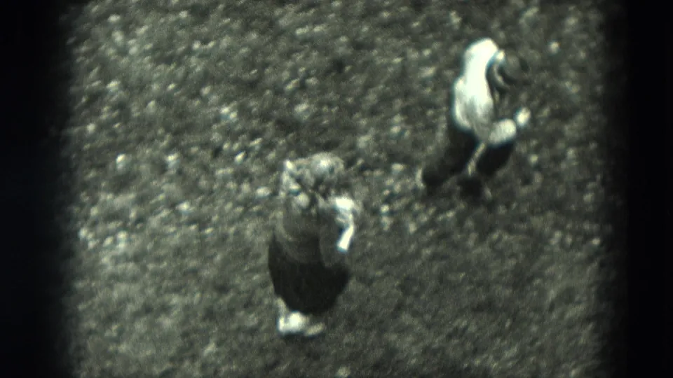 Overhead 1951 West Germany home-movie frame of two children approaching each other on a gravel yard during informal outdoor play.