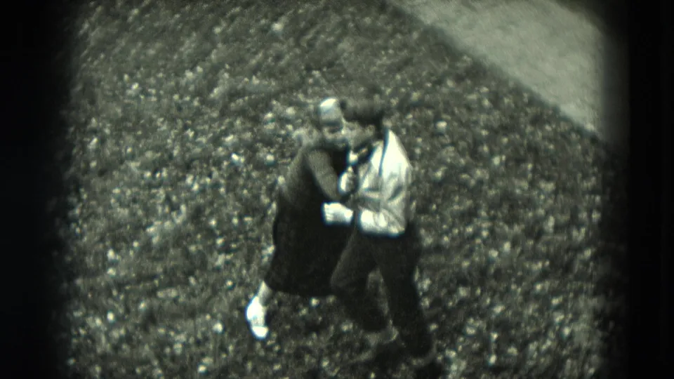 In 1951 West Germany home-movie footage, a man in a light shirt and a woman in a dark dress appear to dance closely on a gravel path.