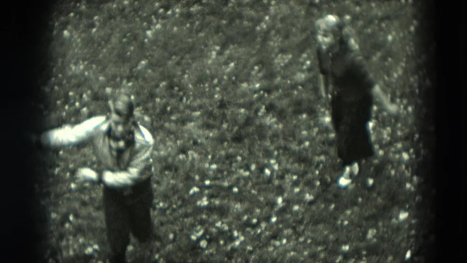 High-angle 1951 Germany home-movie frame showing a boy in a light shirt and a girl in a dark dress on grass.