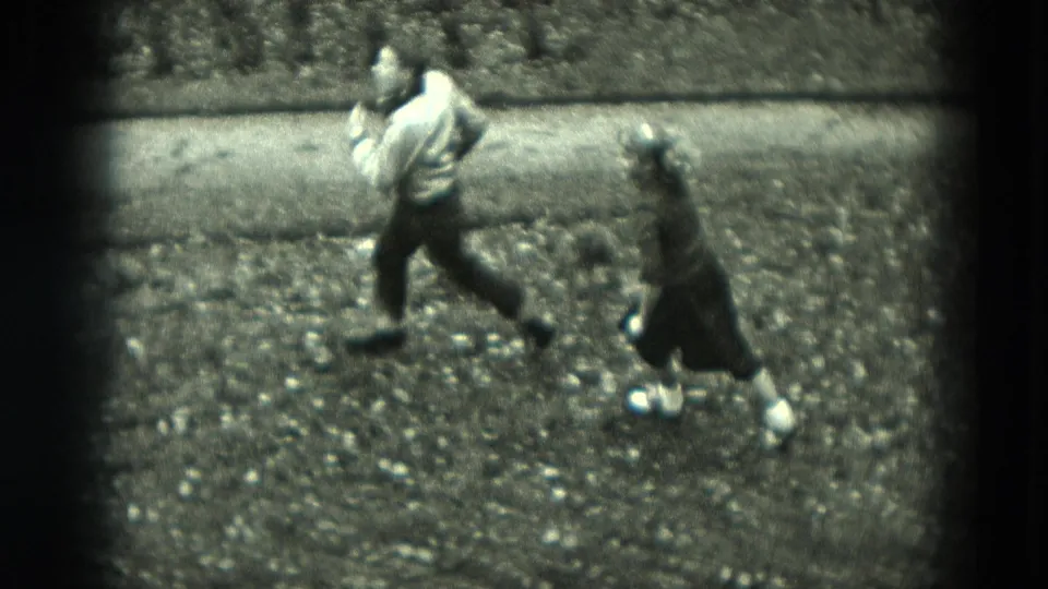 The boy and girl run across the yard beside a narrow path in this high-angle 8mm home-movie frame.