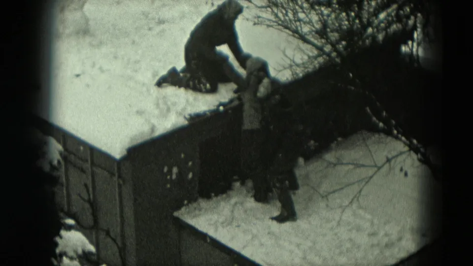 A bundled figure on a snow-covered roof reaches down toward another person below in a 1951 Germany home-movie scene.