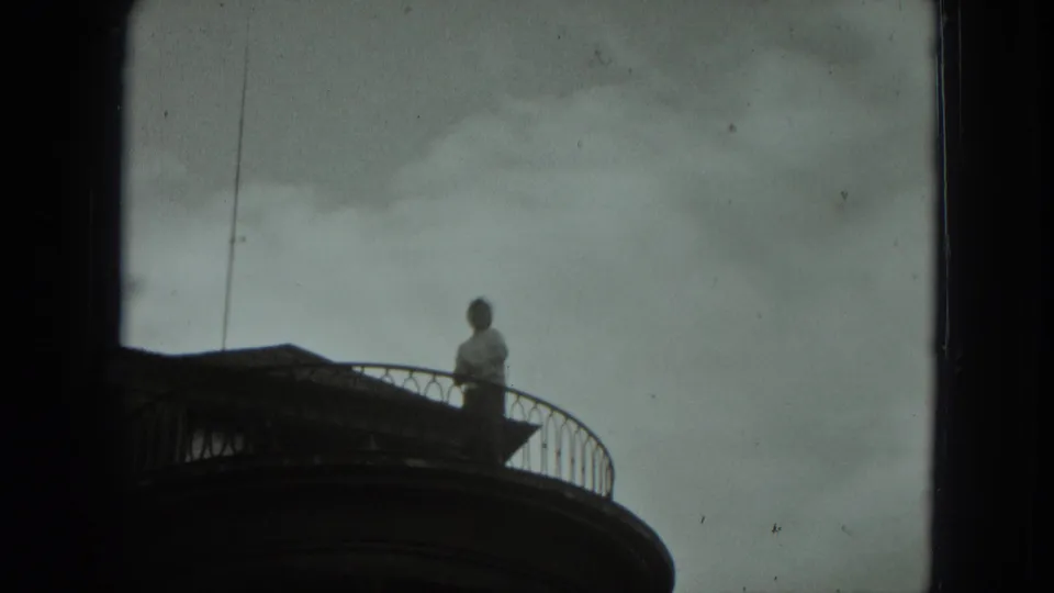 In 1951 West Germany home-movie footage, a person stands on a curved residential balcony above the camera.